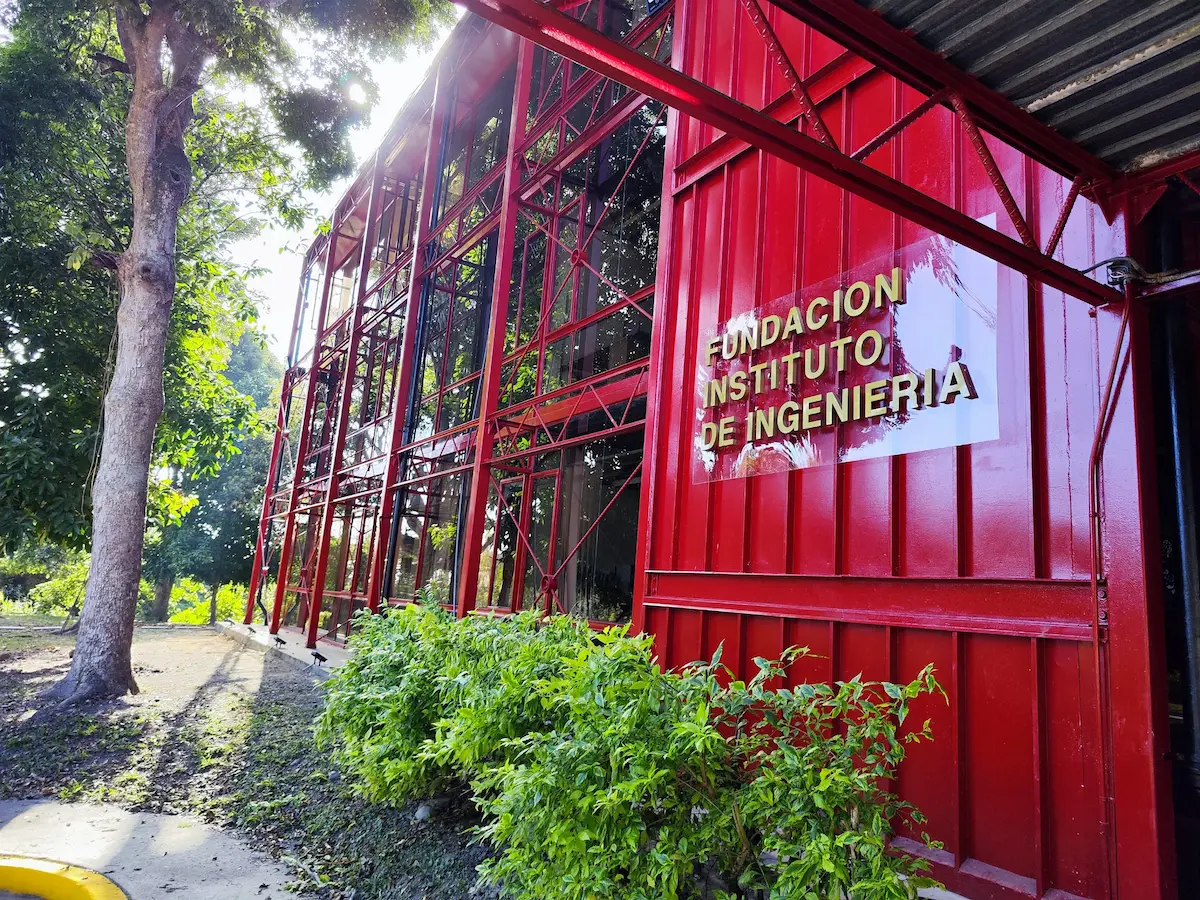 Sede de la Fundación Instituto de Ingeniería (FIIIDT). Estructura metálica roja rodeada de naturaleza con el letrero visible de la institución en Caracas